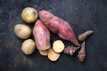 Batat, topinambur, ziemniak na ciemnym tle.