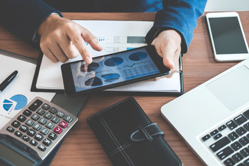 Businessman hands using text information on digital tablet to analyze financial statistical chart...