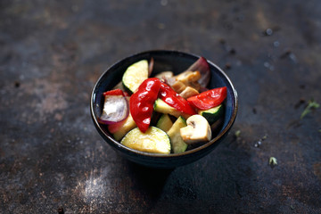 Grillowane warzywa Papryka, pieczarki cukinia w miseczce na ciemnym tle.