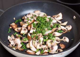 Chopped champignons and parsley on frying pan