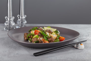 Poke with beef and rice on a beautiful plate with candles and a glass of drink. Hawaiian cuisine.