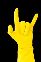 Hand in yellow rubber glove on black background showing gesture sign of the horns, metal horns, devil horns, rock horns. Isolated glove for cleaning on black background.