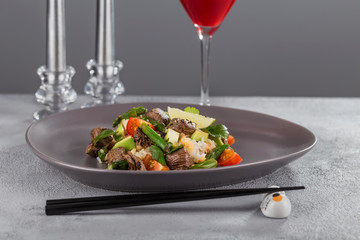 Poke with beef and rice on a beautiful plate with candles and a glass of drink. Hawaiian cuisine.