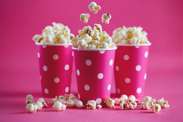 Pink polka dot paper cups with tasty popcorn. © Melica