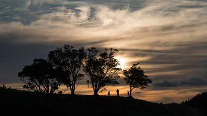 Fototapeta na wymiar Silhouette image of people walking at the top of Mt Eden at Sunset