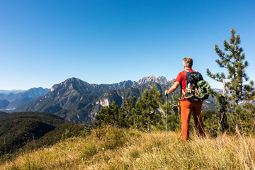Naklejka na ściany i meble Man hiker is admiring the range mountains landscape.