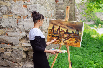 The female artist paints a picture of an ancient fortress