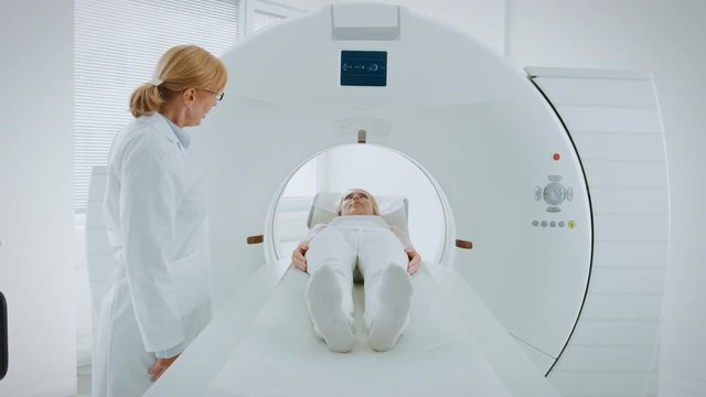 In Medical Laboratory Female Radiologist Controls MRI or CT or PET Scan with Female Patient Undergoing Procedure. Doctor Conducts Emergency Scanning with Advanced Medical Technologies. 