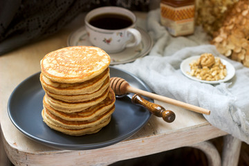 Pancakes with banana, nuts and honey, served with tea. Rustic style.