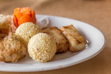 The set of fried dimsum , Hongkong food with the various of fried flour menu with different shape such as round and panel with the orange carrot flower in the white dish on the table. 