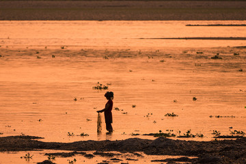 Fototapeta na wymiar Asian Woman fishing in the river, silhouette at sunset
