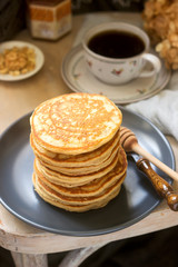 Pancakes with banana, nuts and honey, served with tea. Rustic style.