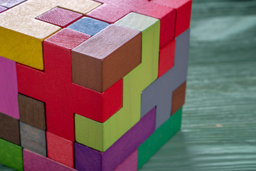 The cube is made up of multi-colored wooden shapes.