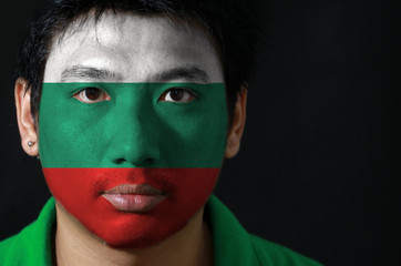 Portrait of a man with the flag of the Bulgaria painted on his face on black background, white green and red color.