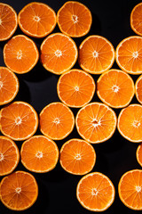 full frame of arranged cut tangerines halves on black background