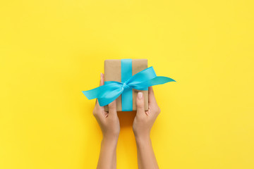 Woman hands give wrapped valentine or other holiday handmade present in paper with blue ribbon....