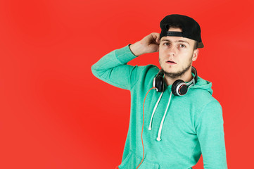 Young cute emotional guy in headphones listens to music and sings on isolated red background