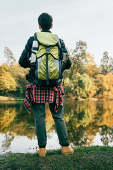 rear view of traveller with backpack on autumnal background
