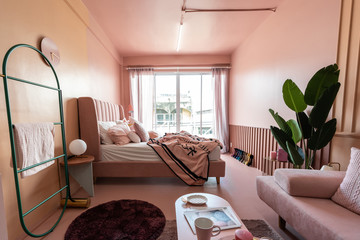 Cozy pink bedroom corner decorated with comfortable pink pillows and fluffy pink blanket setting on...