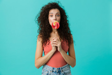 Portrait of european woman 20s wearing casual clothing eating lollipop, isolated over blue background