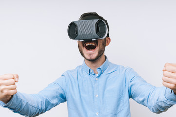 Amazed man wearing VR glasses and screaming over white background