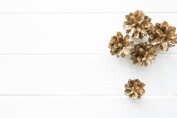 Golden pine cones on white wooden table background, top view, copy space.