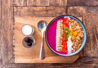 Dragon fruit smoothie bowl with strawberries, granola, chia seeds and banana.