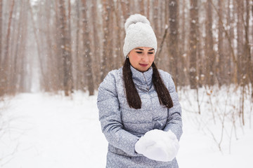Walks, season and people concept - happy young woman holding snow in winter park