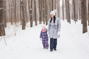 Fototapeta na wymiar Winter, family and people concept - mother is walking with her daughter in winter forest.
