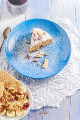 A piece of banana cake with nuts, sesame and cranberry on a wooden table