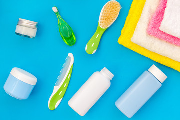 Baby care. Bath cosmetics and accessories for child. Shampoo, gel, cream, towel, brush on blue background top view pattern