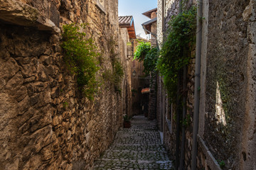 A narrow street paved with stone among stone houses in a medieval small town Sermoneta not far from Rome