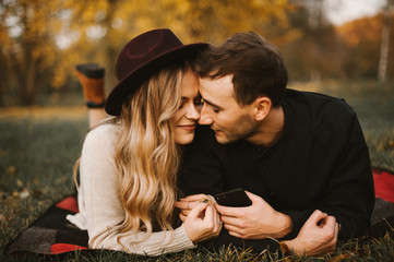 Happy lovely young couple laying on grass in park. romantic beautiful couple in autumn time