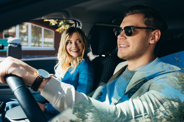 smiling woman at boyfriend driving car during vacation