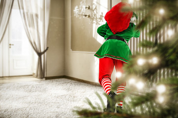 Christmas elf in home interior with big window and christmas tree 
