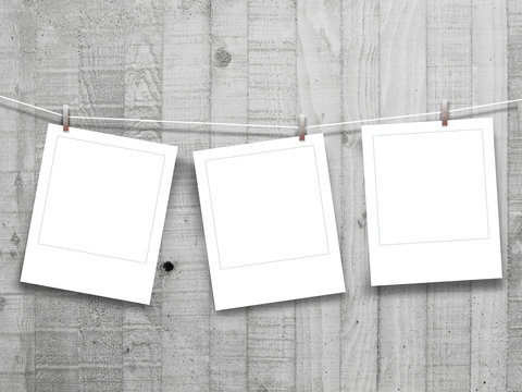 Three square blank instant photo frames on grey concrete wall background