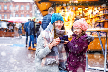 Young woman and cute kid girl with cup of steaming hot chocolate or children punch