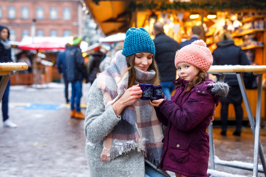Young woman and cute kid girl with cup of steaming hot chocolate or children punch
