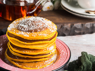 Pumpkin pancakes stack served with chocolate and coconut shreds