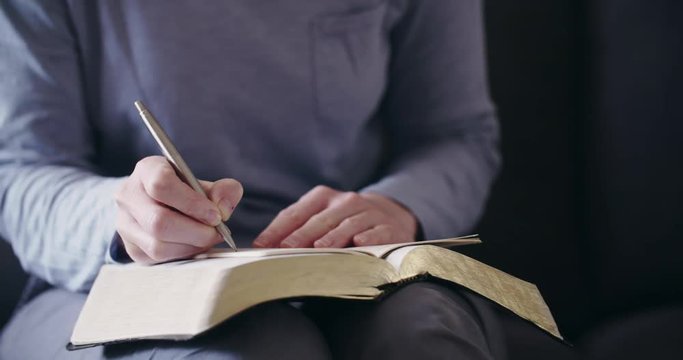 Dolly shot of a woman studying the Bible and praying at home.