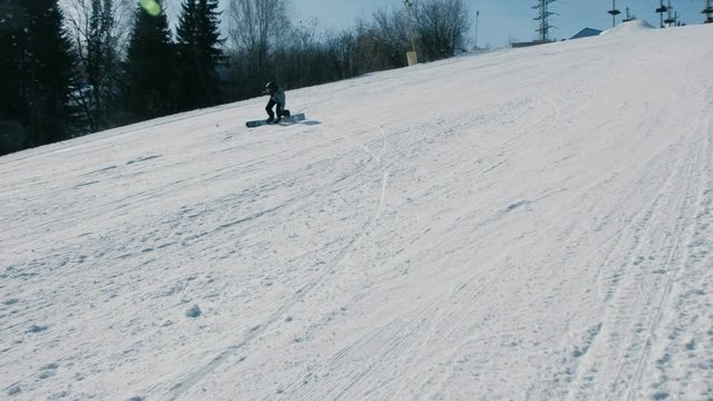 Teenage boy of 12 years in grey cloth sliding on a snowboard from snow descent next sky lift.