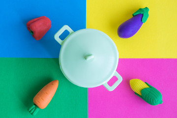 Vegetables and pot abstract against multicolored background.