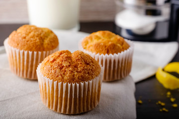 Fresh homemade muffins with lemon, milk and sugar on rustic background.