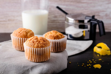 Fresh homemade muffins with lemon, milk and sugar on rustic background.