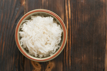 Sauerkraut in a plate on a wooden background.