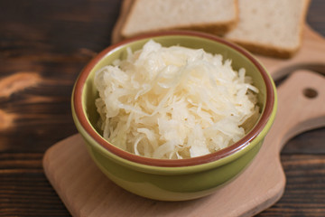 Sauerkraut in a plate on a wooden background.