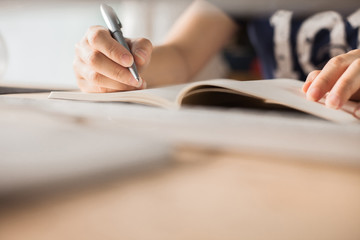 Hands of a Business woman is writing book as notepad or Take notes on Her wooden table desk  . Business Success Working at home office with notebook and computer for marketing and part time Concept.