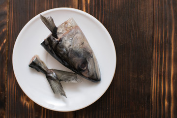 Raw head and tail of mackerel fish on a plate. The remains of butchering fish.