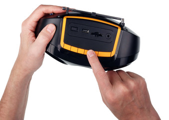 An elderly man with his fingers turns on a small radio device. Isolated