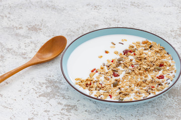 Granola, oatmeal with milk, honey and strawberry on blue plate